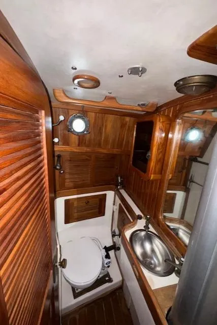 Slide: The Image of 1986 Cabo Rico CB38 yacht bathroom with wooden interior, stainless steel sink, and porthole window. - 24