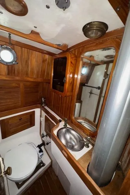 Slide: The Image of 1986 Cabo Rico CB38 yacht bathroom with wooden cabinetry, stainless steel sink, and porthole window. - 26