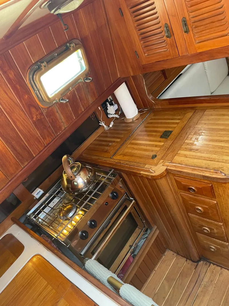 Slide: The Image of 1986 Cabo Rico CB38 yacht interior with wooden cabinetry and compact kitchen area. - 9