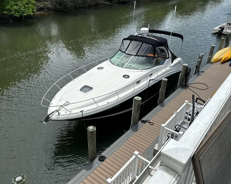 Slide: The Image of 2003 Sea Ray 340 Sundancer docked by a wooden pier on a calm river. - 1