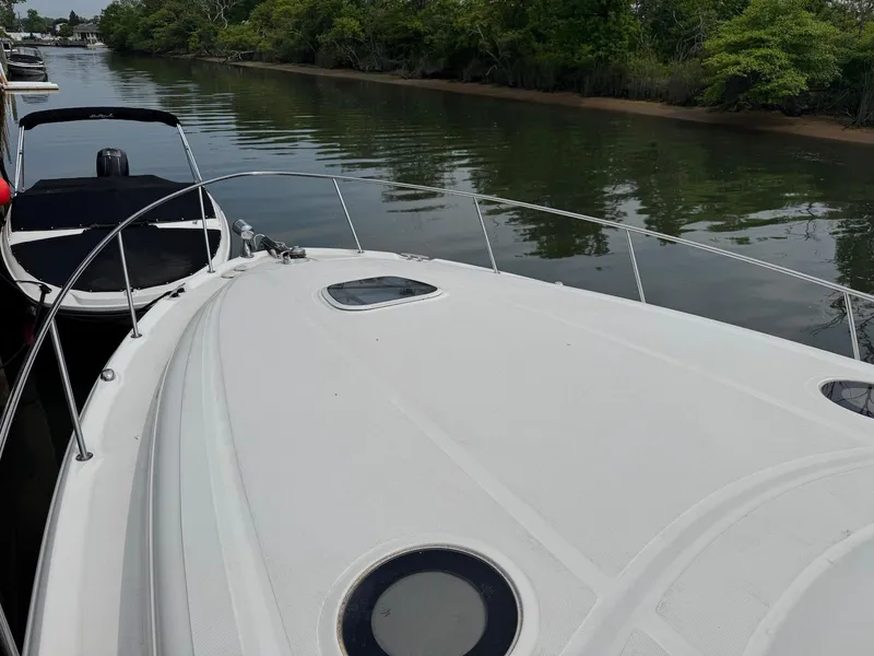 Slide: The Image of 2003 Sea Ray 340 Sundancer yacht on calm river, surrounded by lush greenery. - 16