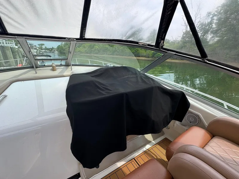 Slide: The Image of 2003 Sea Ray 340 Sundancer cockpit with covered dashboard, leather seats, and scenic waterway view. - 17