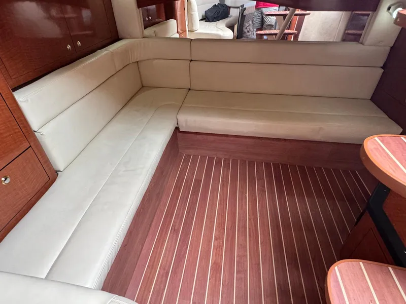 Slide: The Image of 2003 Sea Ray 340 Sundancer interior with beige seating and wooden flooring. - 24