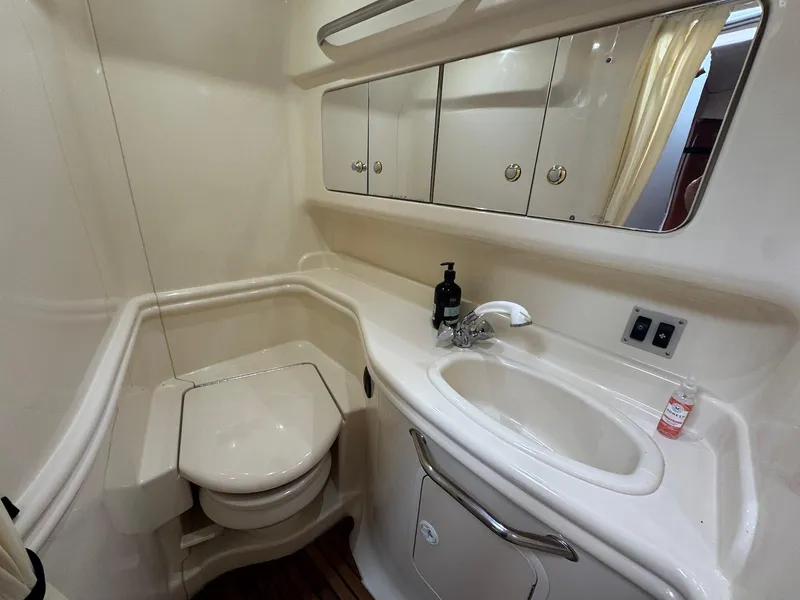 Slide: The Image of 2003 Sea Ray 340 Sundancer bathroom with sink, toilet, and mirrored cabinets. - 26