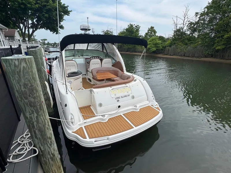 Slide: The Image of 2003 Sea Ray 340 Sundancer docked in a serene waterway, featuring a spacious deck. - 4