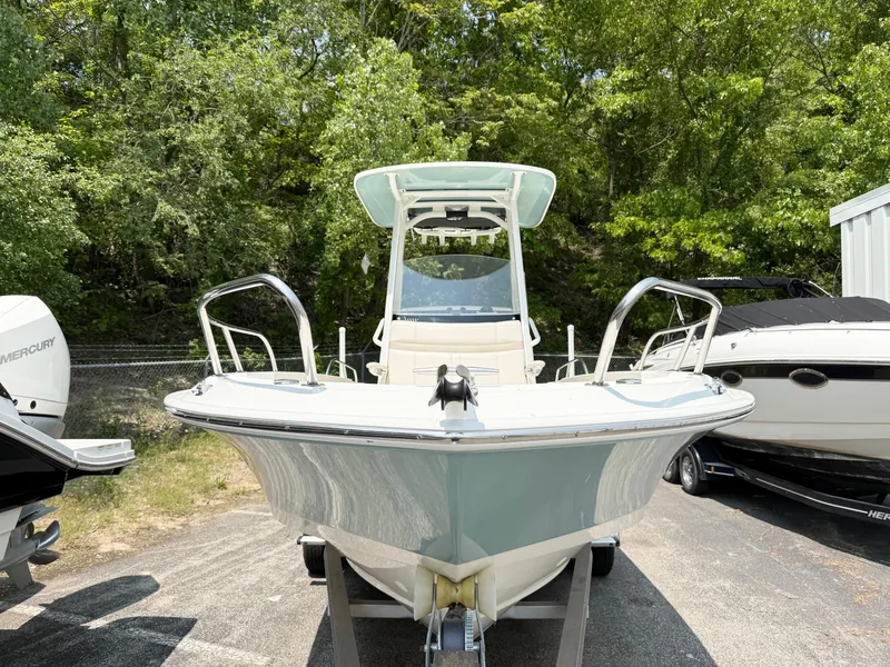 Slide: The Image of 2022 Boston Whaler 220 Dauntless boat, front view, parked outdoors with trees in background. - 2
