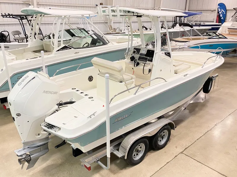 Slide: The Image of 2022 Boston Whaler 220 Dauntless boat on trailer in showroom, featuring sleek design and Mercury engine. - 20