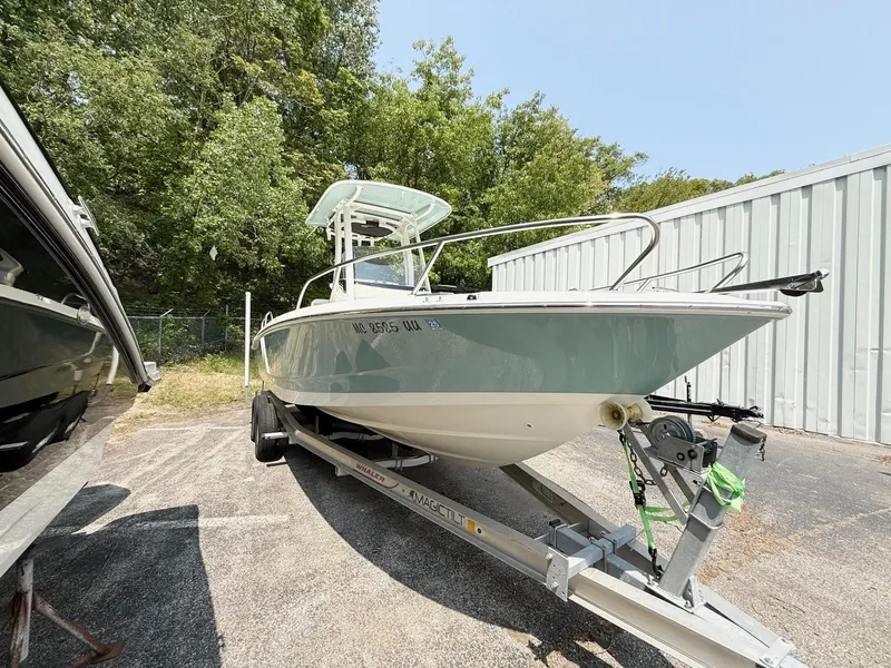 Slide: The Image of 2022 Boston Whaler 220 Dauntless boat on trailer, parked outdoors near trees and a building. - 3