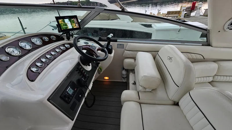 Slide: The Image of 2003 Monterey 322 Cruiser cockpit with steering wheel, gauges, and plush seating by the water. - 11