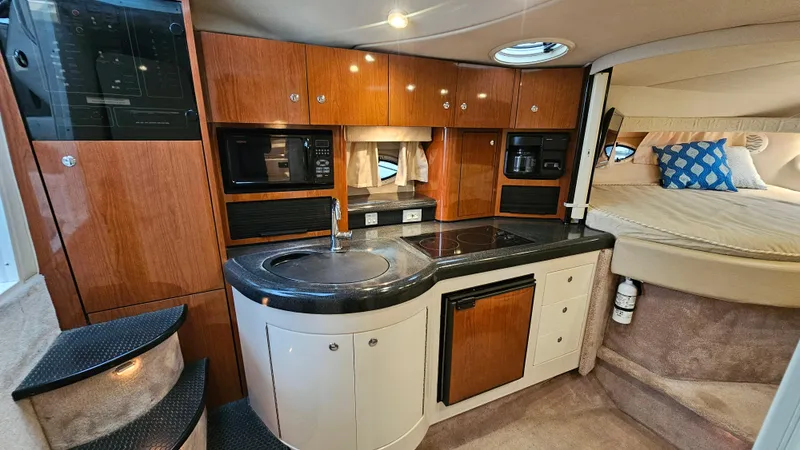 Slide: The Image of 2003 Monterey 322 Cruiser interior with kitchenette, wood cabinets, and cozy sleeping area. - 16