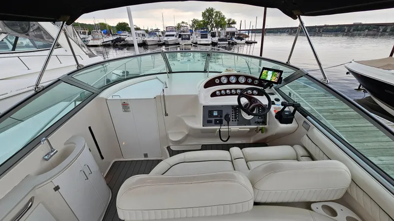 Slide: The Image of 2003 Monterey 322 Cruiser interior with helm, white seating, and marina view. - 8