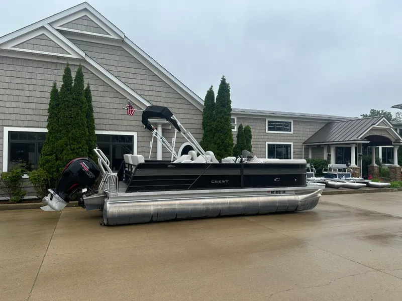 The Image of 2022 Crest Classic DLX SLRC 220 pontoon boat parked outside a building on a cloudy day. - 0