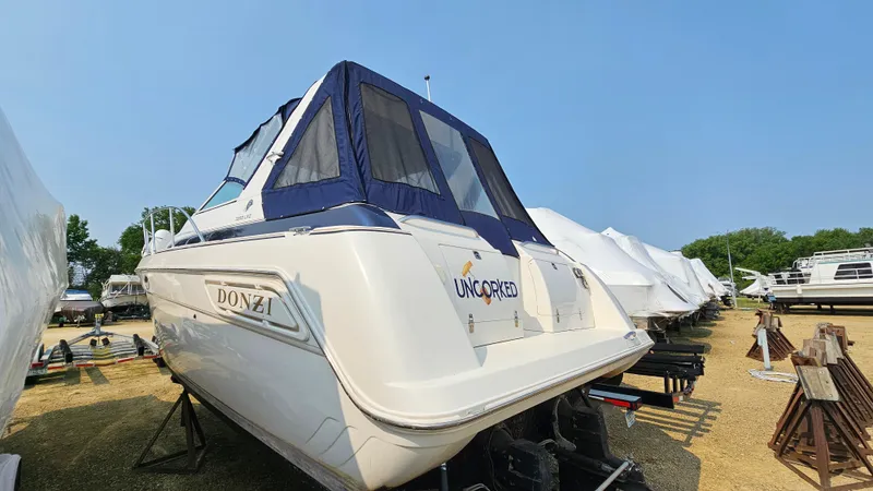 Slide: The Image of 1997 Donzi 3250 LXC boat with blue canopy, parked on a gravel lot. - 3