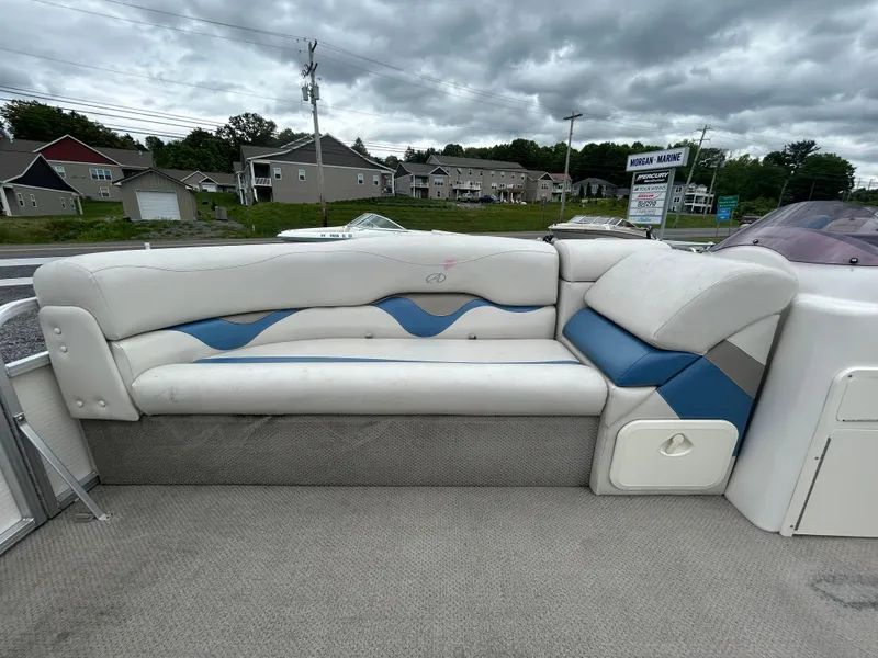 Slide: The Image of 2007 Avalon Windjammer 18' boat interior with white and blue seating under cloudy skies. - 11