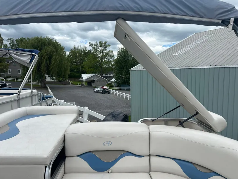 Slide: The Image of 2007 Avalon Windjammer 18' boat with blue and white seating, docked near a shed. - 12