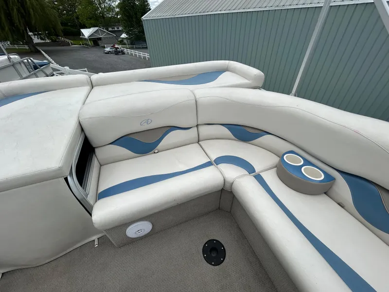 Slide: The Image of 2007 Avalon Windjammer 18' boat interior with white and blue cushioned seating and cup holders. - 13
