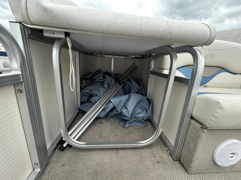 Slide: The Image of Storage compartment in a 2007 Avalon Windjammer boat, containing metal poles and fabric. - 14