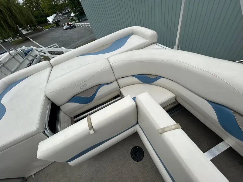 Slide: The Image of 2007 Avalon Windjammer 18' boat with white and blue seating, docked near a building. - 22