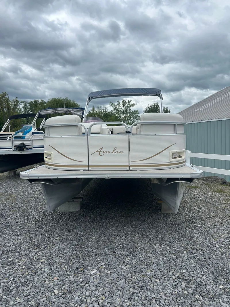 Slide: The Image of 2007 Avalon Windjammer 18' pontoon boat on gravel, under cloudy sky. - 3