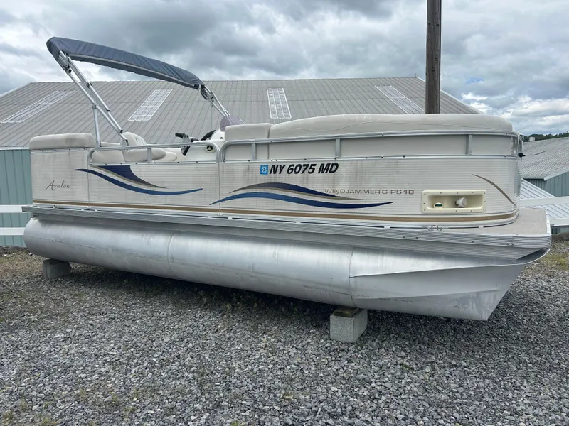 Slide: The Image of 2007 Avalon Windjammer 18' pontoon boat on gravel, with blue wave design. - 4