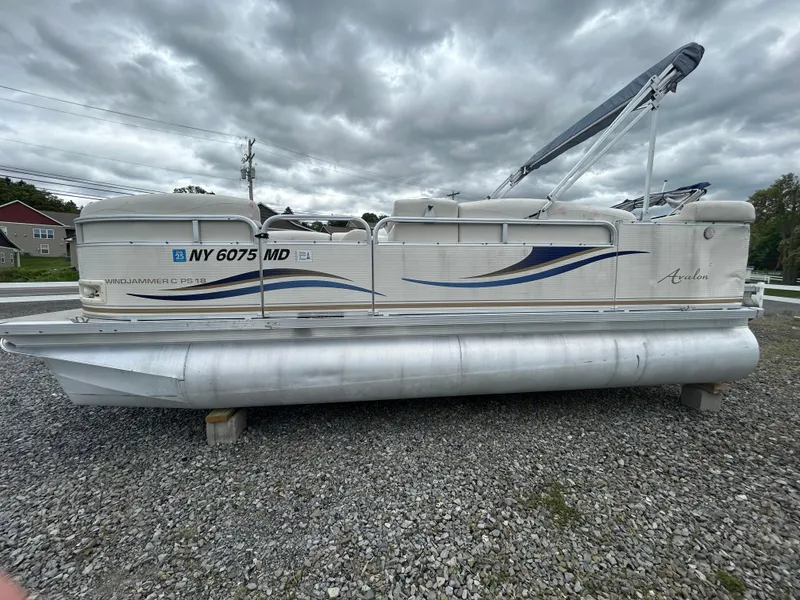 Slide: The Image of 2007 Avalon Windjammer 18' pontoon boat on gravel, under cloudy skies. - 5