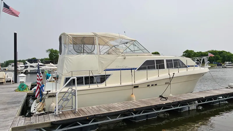 The Image of 1986 Chris-Craft 381 Catalina yacht docked at a marina, featuring a beige exterior and covered deck. - 1