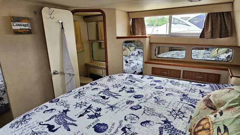 Slide: The Image of 1986 Chris-Craft 381 Catalina cabin interior with nautical-themed bedding and mirrored accents. - 20