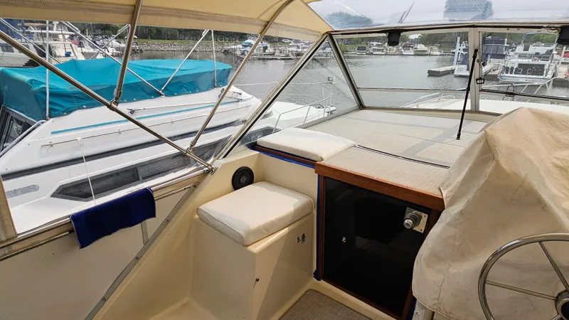 Slide: The Image of 1986 Chris-Craft 381 Catalina boat interior with marina view, featuring helm and seating area. - 8