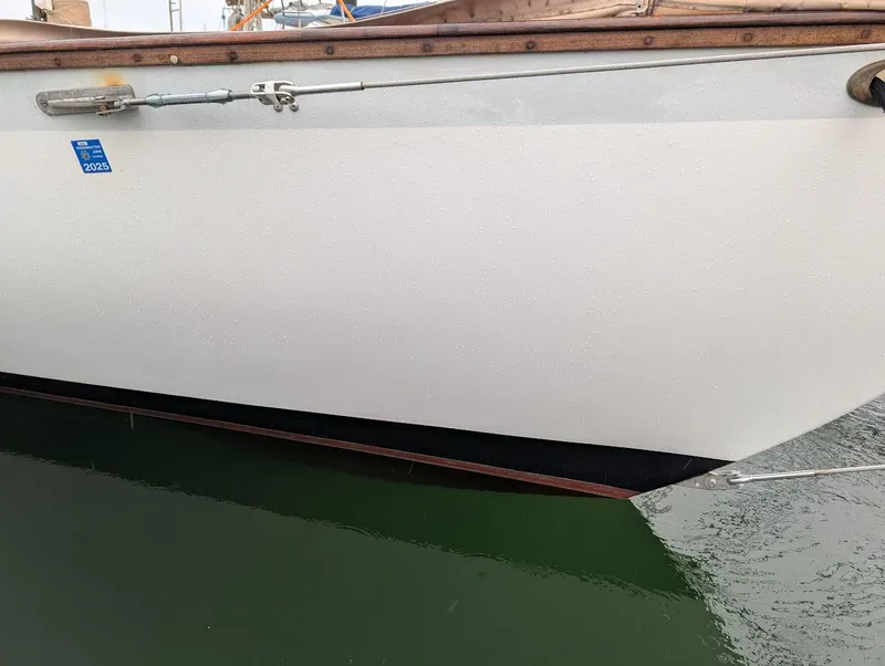 Slide: The Image of 1977 Alajuela 38 Mk1 sailboat hull in marina, featuring sleek white design and wooden trim. - 18