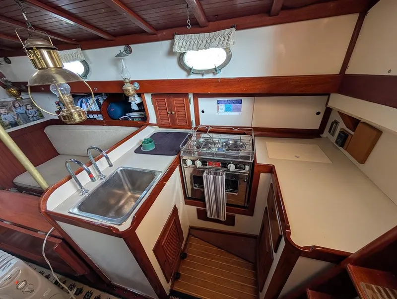 Slide: The Image of Interior of 1977 Alajuela 38 Mk1 sailboat kitchen with stove, sink, and wooden cabinetry. - 31