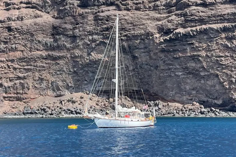 Slide: The Image of Sailboat Alajuela 38 Mk1 (1977) anchored near rocky cliff in clear blue water. - 38