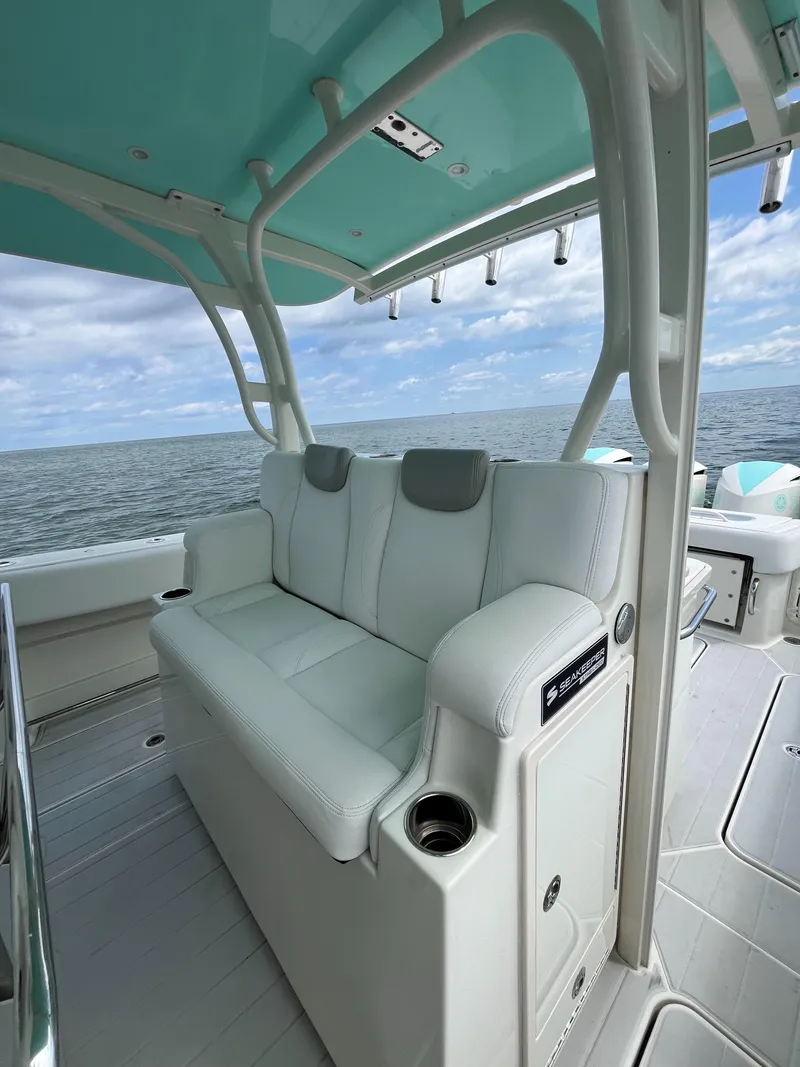 Slide: The Image of 2019 HCB Siesta boat with white seating, ocean view, and teal canopy. - 15
