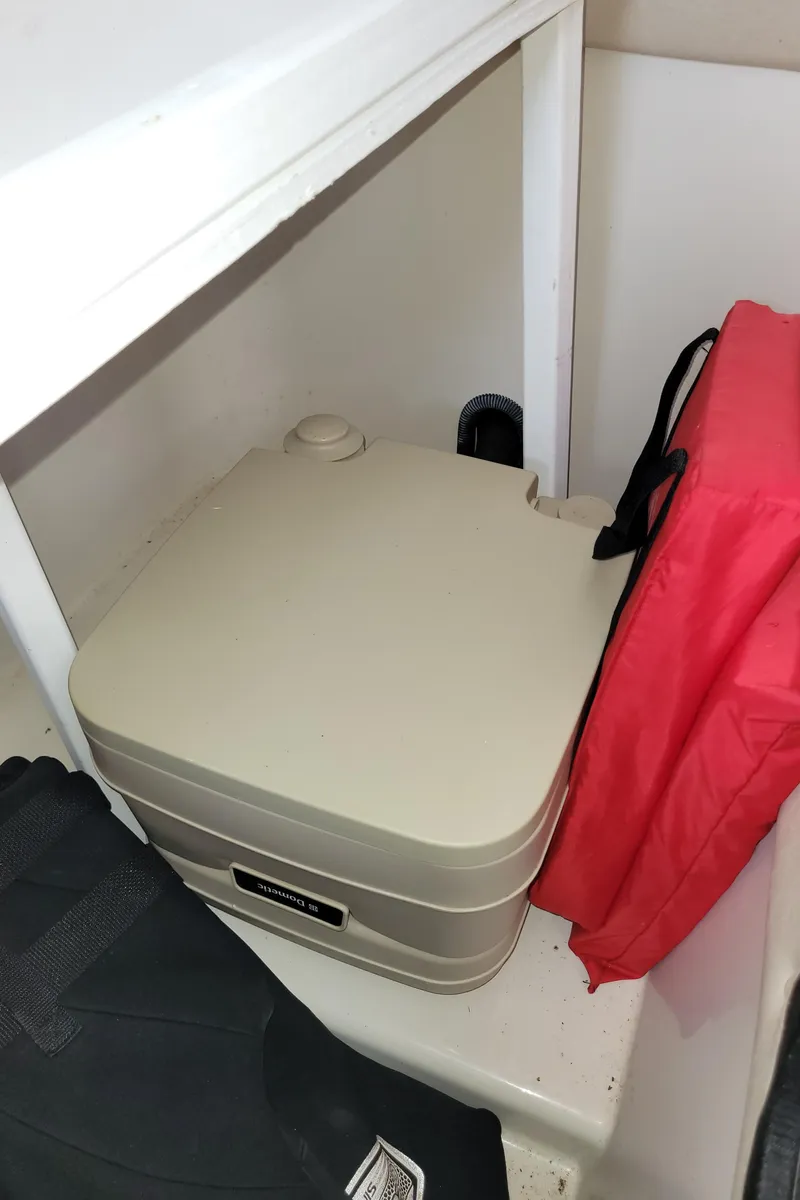 Slide: The Image of 2008 Sea Ray 260 Sundeck interior storage with portable toilet and red life jacket. - 20