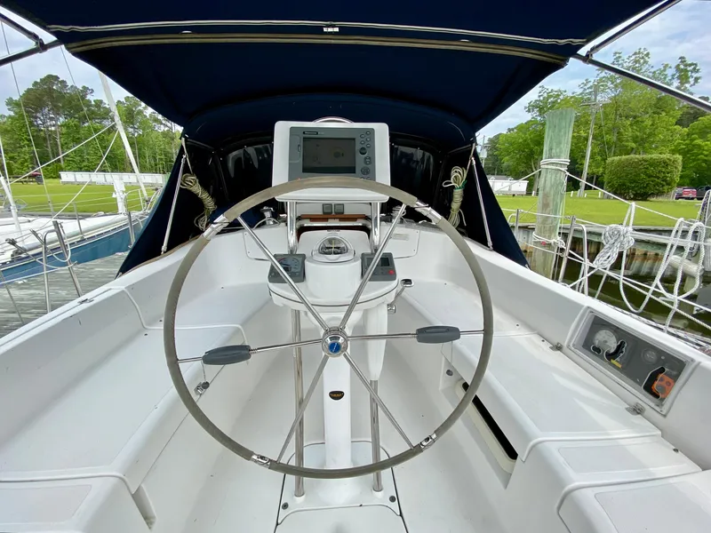 Slide: The Image of Steering wheel of a 2008 Hunter 36-2 sailboat, docked with lush greenery in the background. - 17