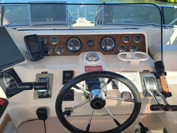Slide: The Image of 1995 Sea Ray 440 Express Bridge helm with gauges, steering wheel, and navigation equipment. - 10