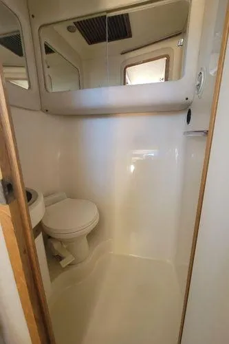 Slide: The Image of 1995 Sea Ray 440 Express Bridge bathroom with toilet and mirrored cabinet. - 19