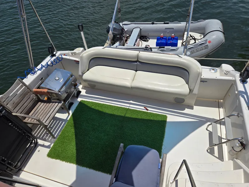 Slide: The Image of 1995 Sea Ray 440 Express Bridge deck with seating, grill, and inflatable boat. - 2