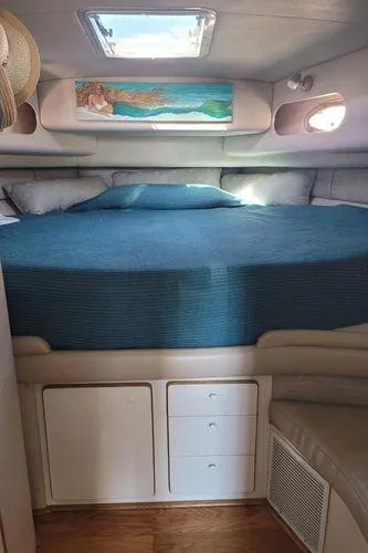 Slide: The Image of 1995 Sea Ray 440 Express Bridge cabin interior with bed, storage, and skylight. - 24
