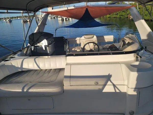 Slide: The Image of 1995 Sea Ray 440 Express Bridge yacht interior with seating and steering wheel, docked on calm water. - 7