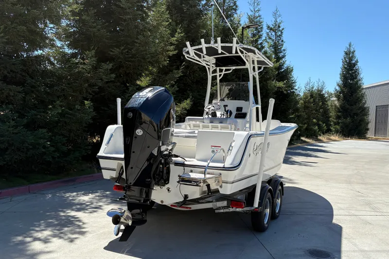Slide: The Image of 2025 Mako 214 Center Console boat on trailer, parked outdoors near trees. - 9