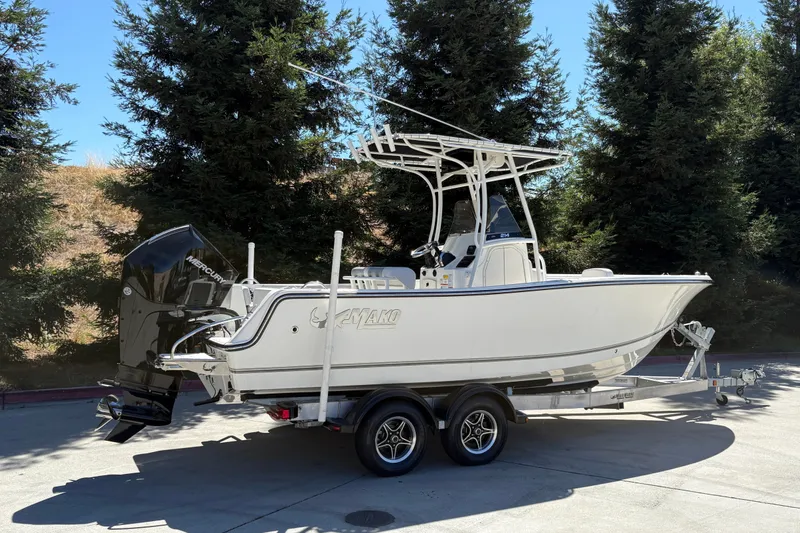 Slide: The Image of 2025 Mako 214 Center Console boat on trailer, parked outdoors with trees in background. - 3