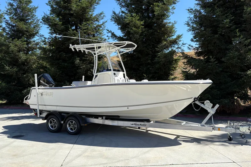 Slide: The Image of 2025 Mako 214 Center Console boat on trailer, parked outdoors near trees. - 2