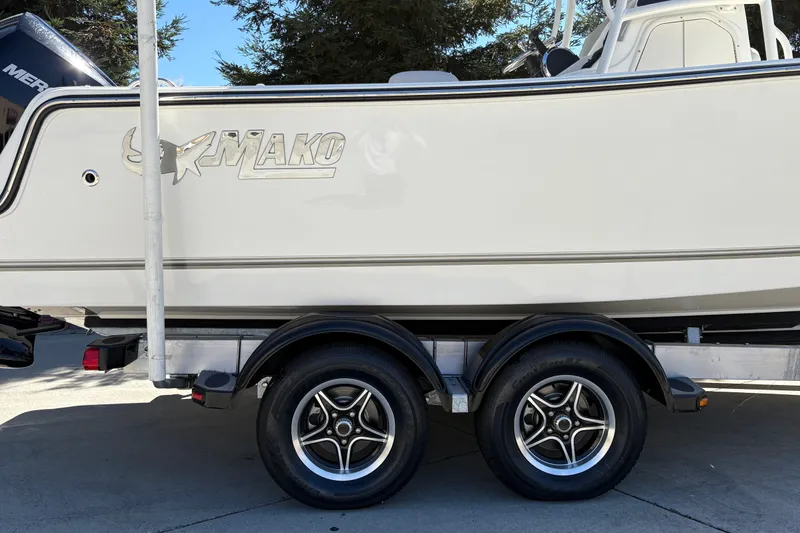 Slide: The Image of 2025 Mako 214 Center Console boat on trailer, showcasing sleek design and dual wheels. - 12