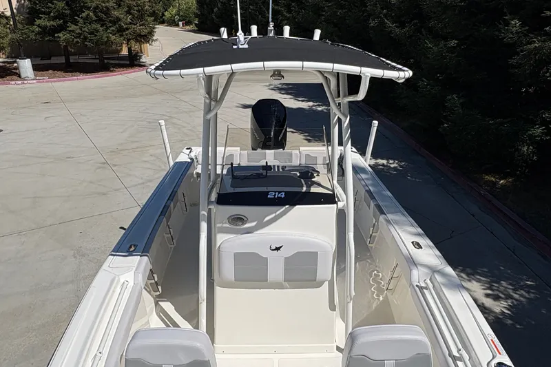 Slide: The Image of 2025 Mako 214 Center Console boat with T-top, parked on concrete driveway. - 15