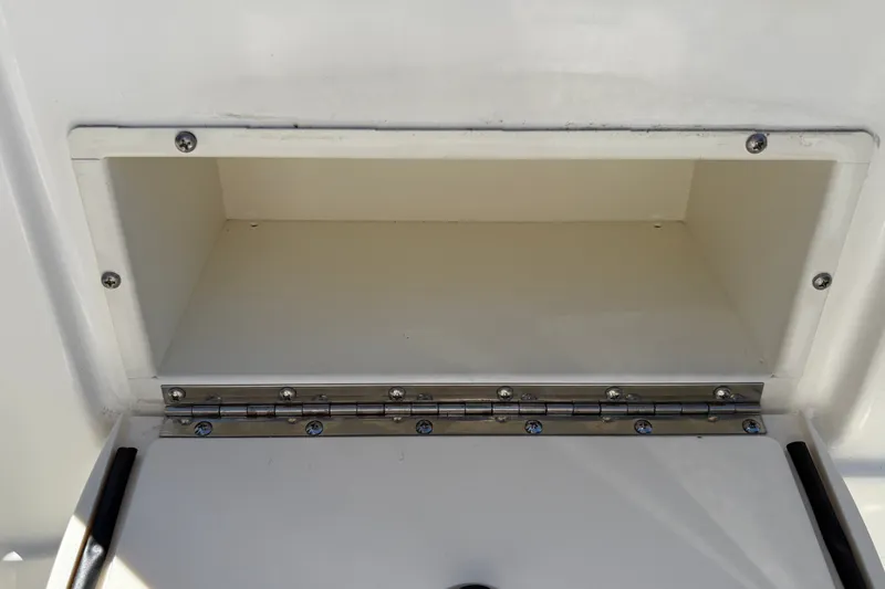 Slide: The Image of Storage compartment of 2025 Mako 214 Center Console boat, featuring a hinged door. - 19