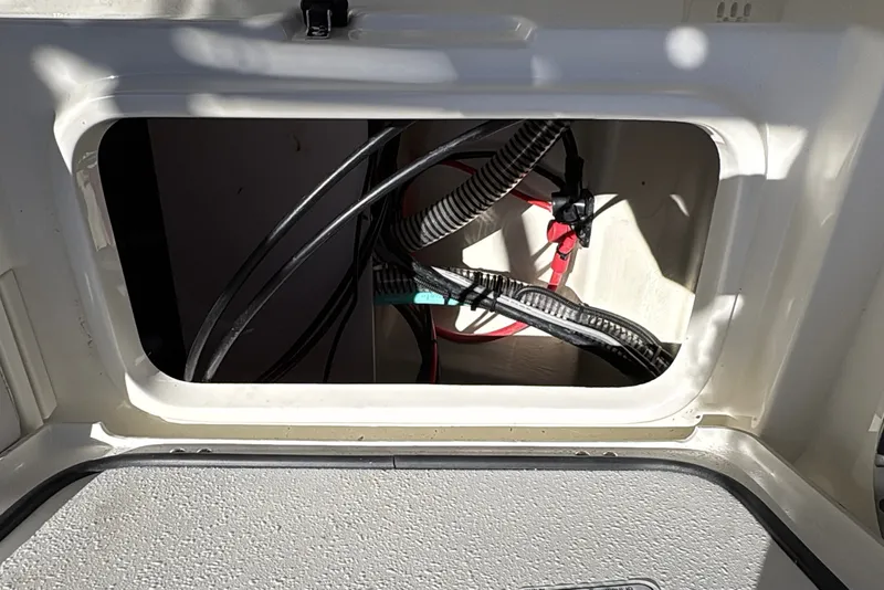 Slide: The Image of Open compartment of 2025 Mako 214 Center Console boat showing wiring and cables. - 13