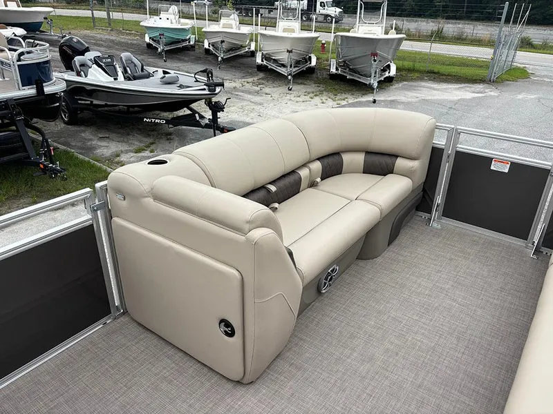 Slide: The Image of 2025 Sun Tracker Party Barge 20 DLX with beige seating, docked near other boats. - 12