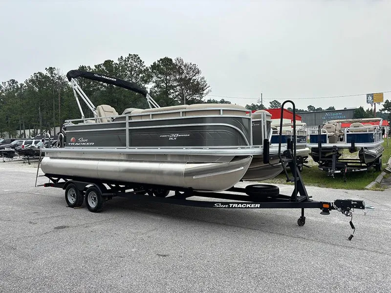 Slide: The Image of 2025 Sun Tracker Party Barge 20 DLX pontoon boat on trailer in outdoor setting. - 5