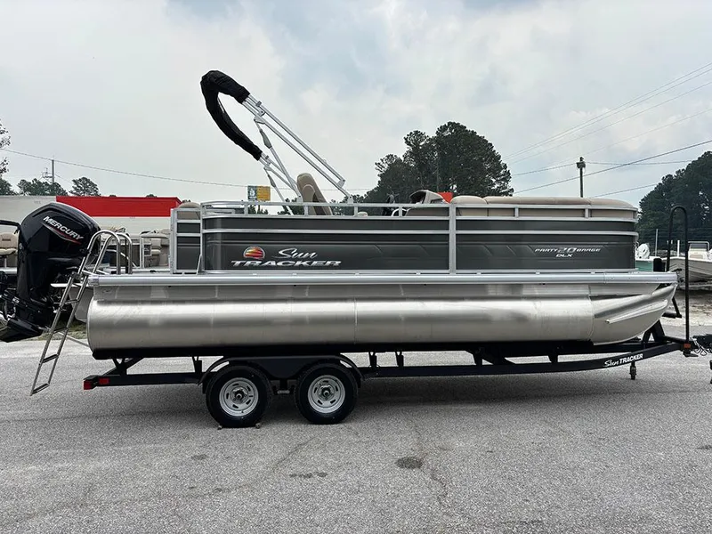 Slide: The Image of 2025 Sun Tracker Party Barge 20 DLX pontoon boat on trailer, parked outdoors. - 6