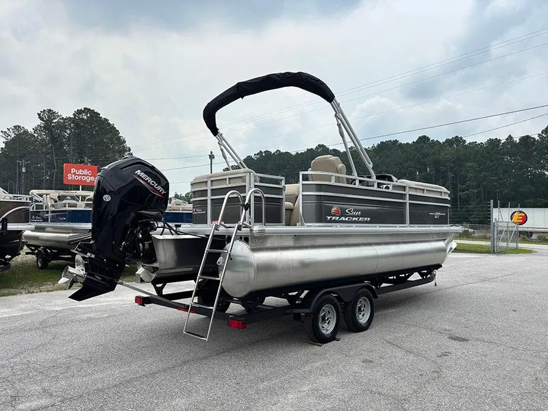 Slide: The Image of 2025 Sun Tracker Party Barge 20 DLX pontoon boat on trailer, outdoor setting. - 7